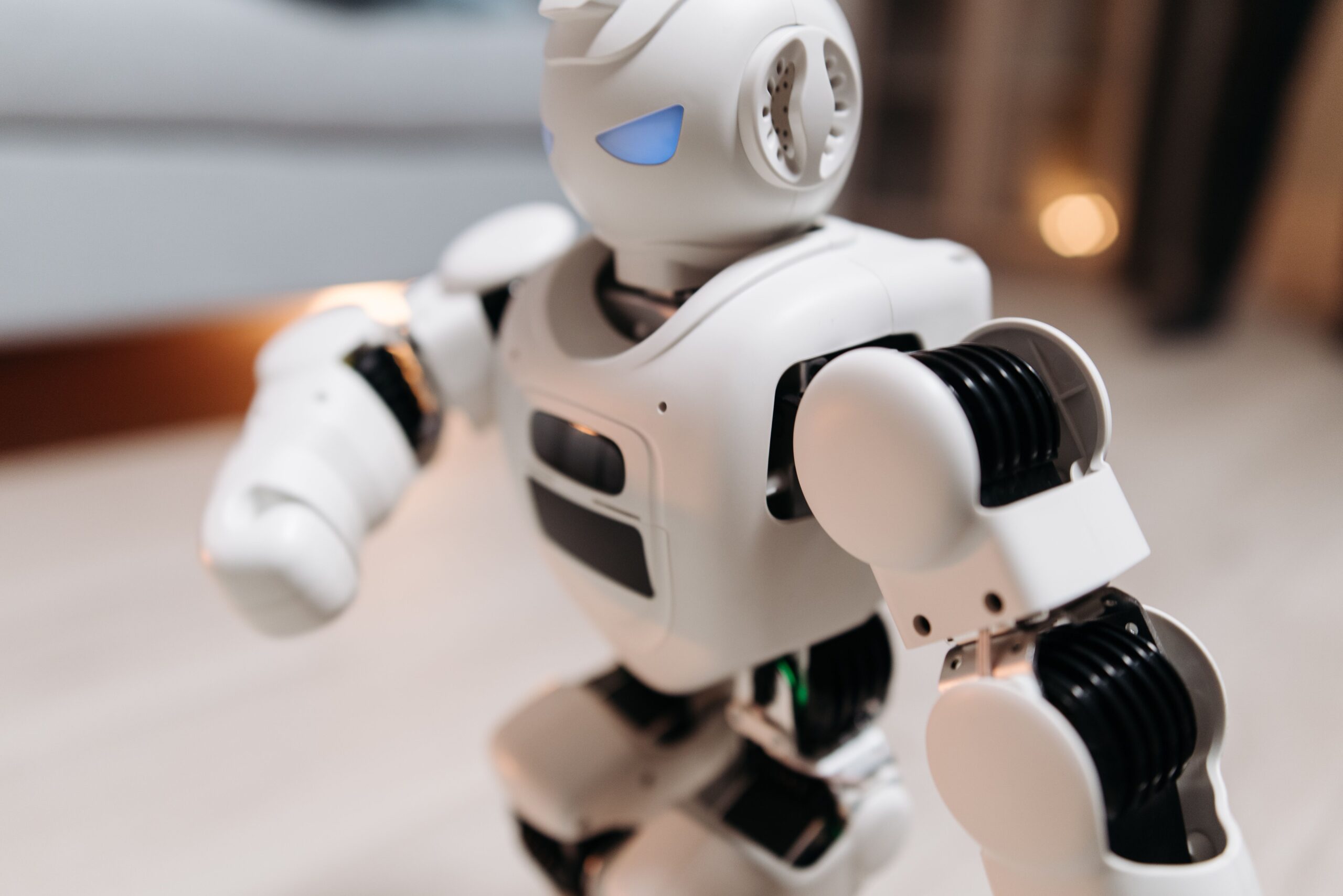 Why Robotics and AI Education are Essential for Schools and Colleges in 2026 Close-up of a futuristic toy robot with blue eyes, showcasing modern technology indoors.